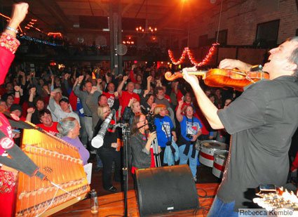 (Daithi Wolfe fiddles and sings “Solidarity Forever” with the crowd at the High Noon Saloon – photo by Rebecca Kemble)